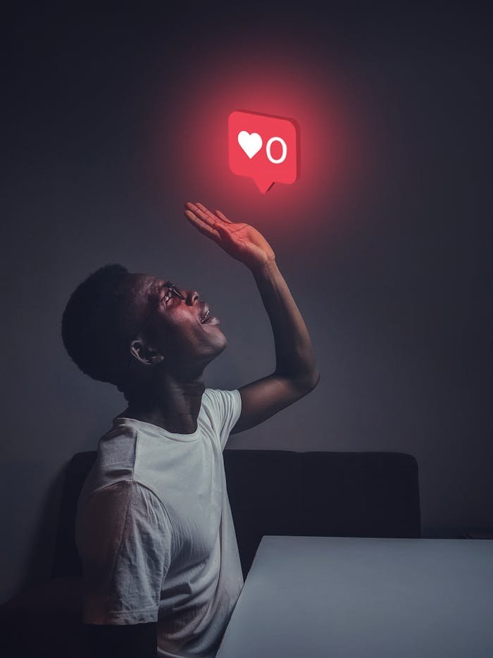 gallery-02 A man sits indoors reaching towards a glowing social media notification icon.