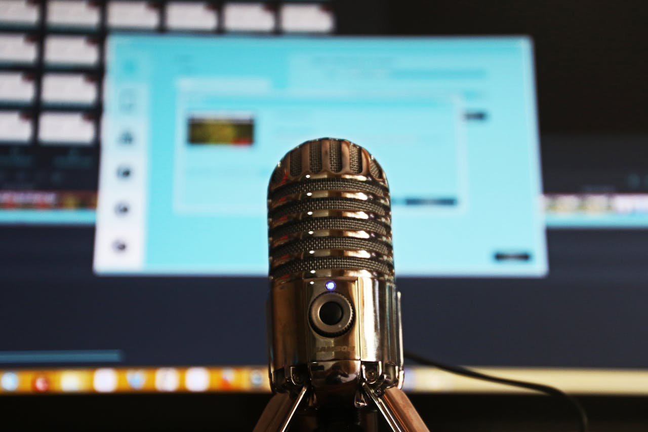 about-img-01 Close-up of a microphone with a blurred computer screen in the background, ideal for podcast themes.
